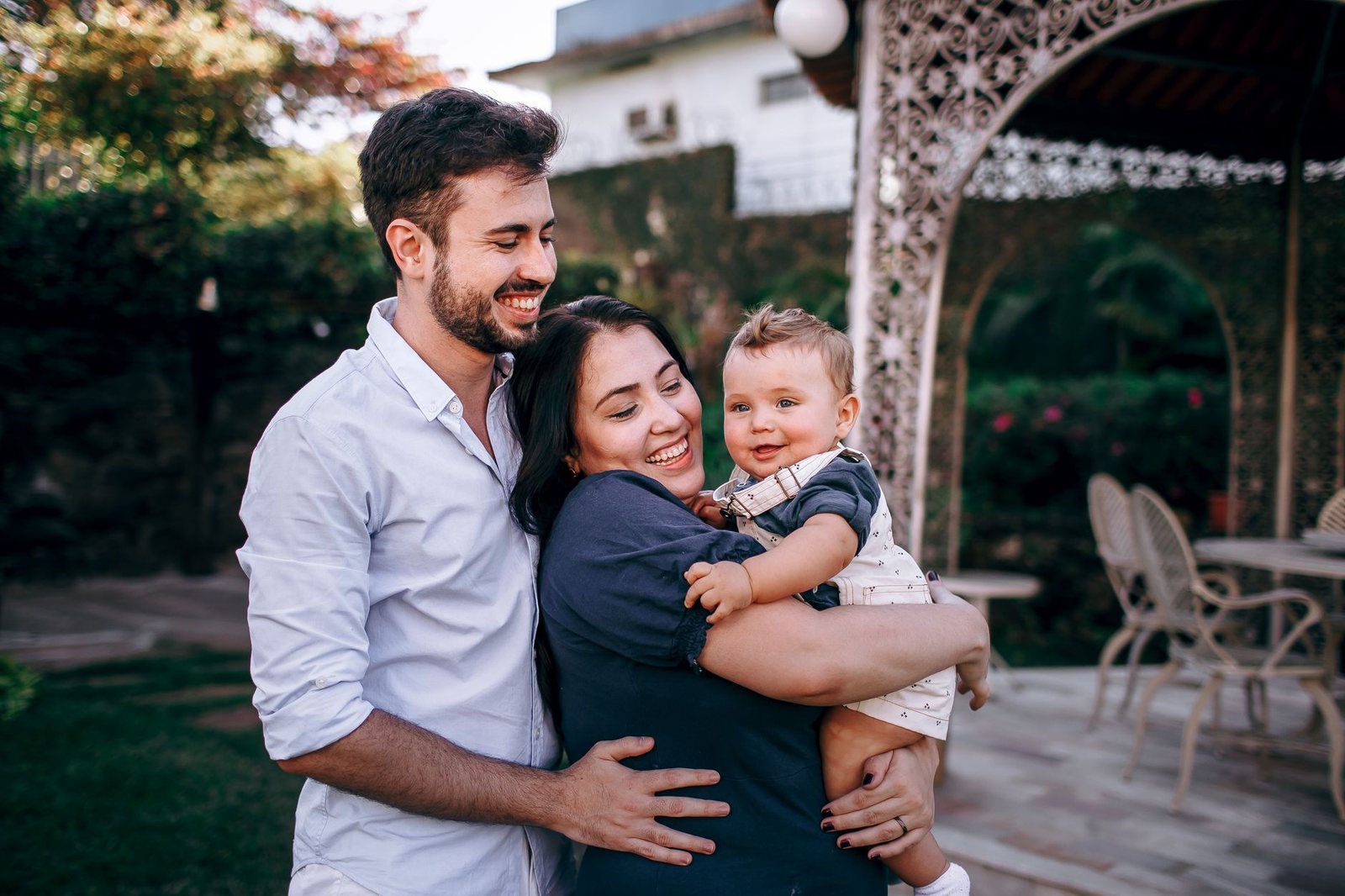 Young parents holding a baby on a garden patio